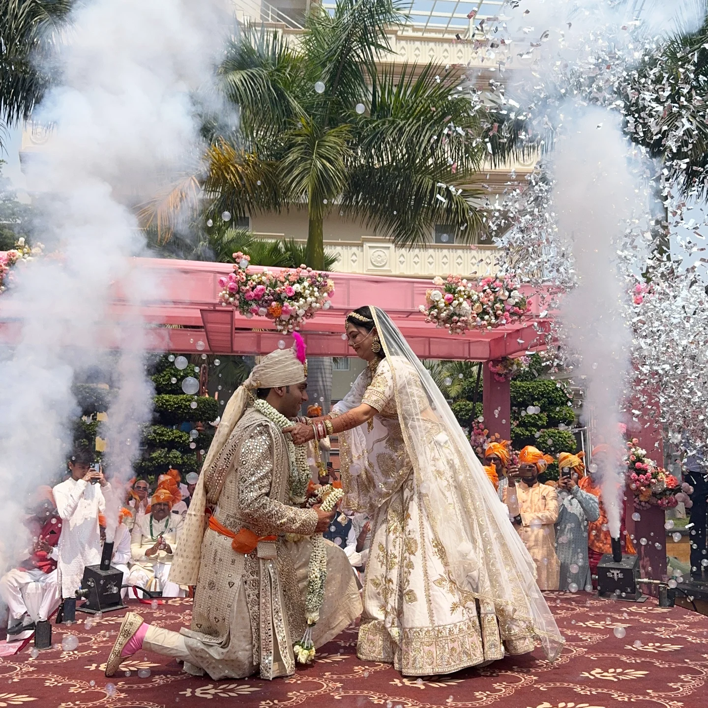 A couple exchanging wedding garlands amid flowers and confetti